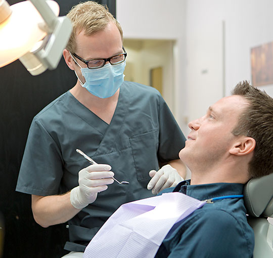 Ein Zahnarzt behandelt einen Patienten am Behandlungsstuhl